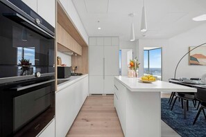 A modern kitchen with white cabinetry, a black oven, and a wooden countertop. - Xia -Jaw-dropping 3BD2BTH Executive City Residence (Melbourne)