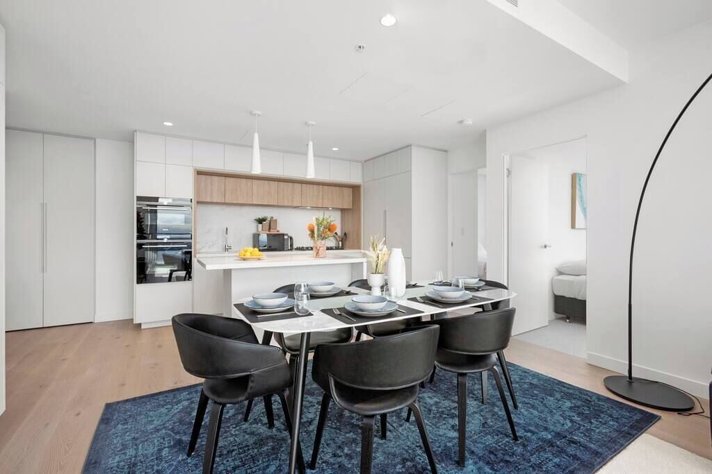 A modern kitchen with white cabinets, a central island, and pendant lighting.