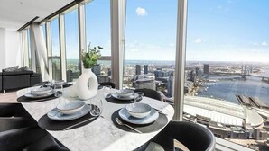 Un comedor con una mesa dispuesta para cuatro, ventanas amplias y vistas a la ciudad y al río.