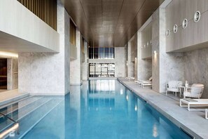 Ein Schwimmbad mit freiem Blick auf Decke und Wände, eine Sitzecke mit Stühlen und ein Fenster für natürliches Licht.