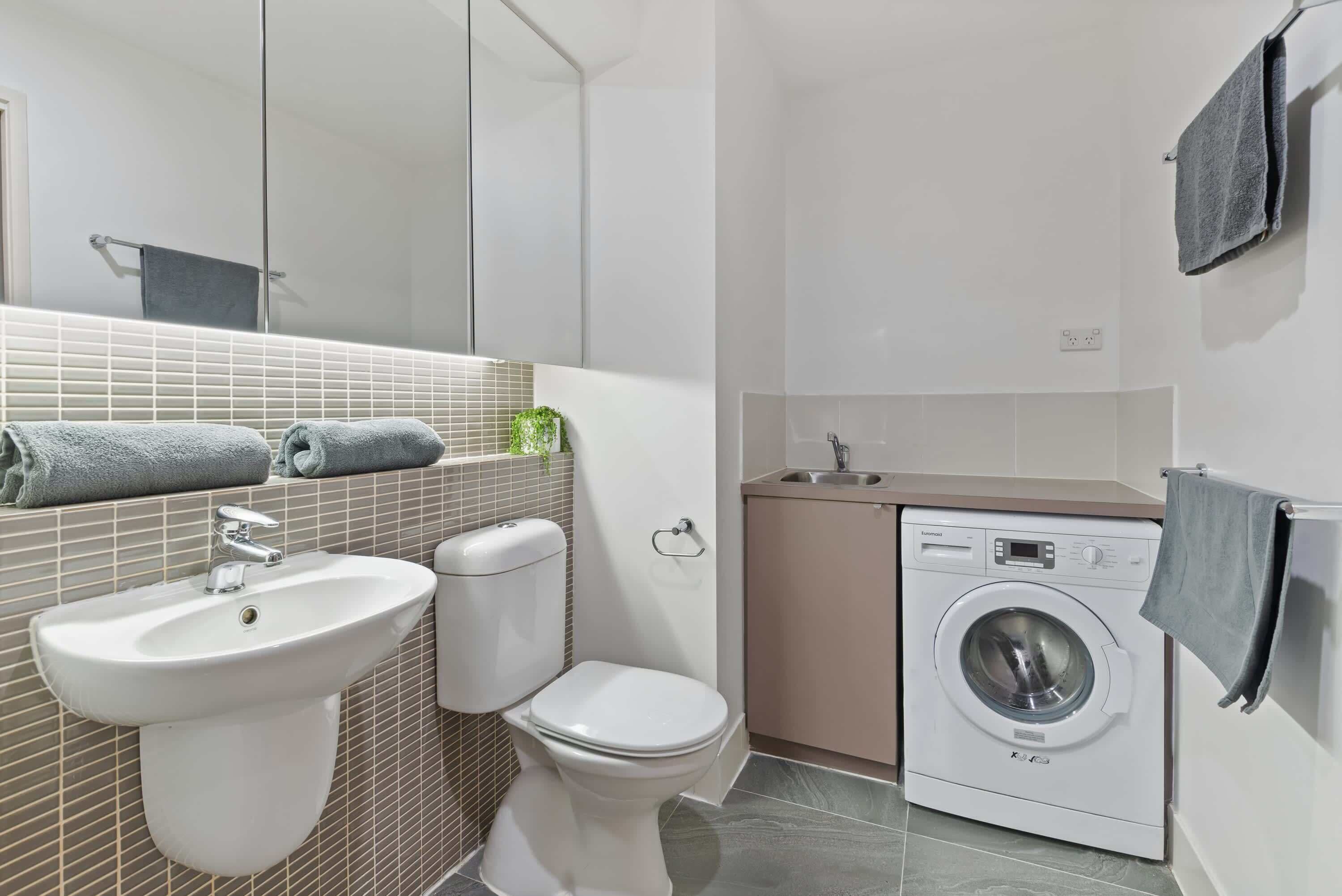 Une petite salle de bain comprenant un lavabo, des toilettes et un lave-linge.