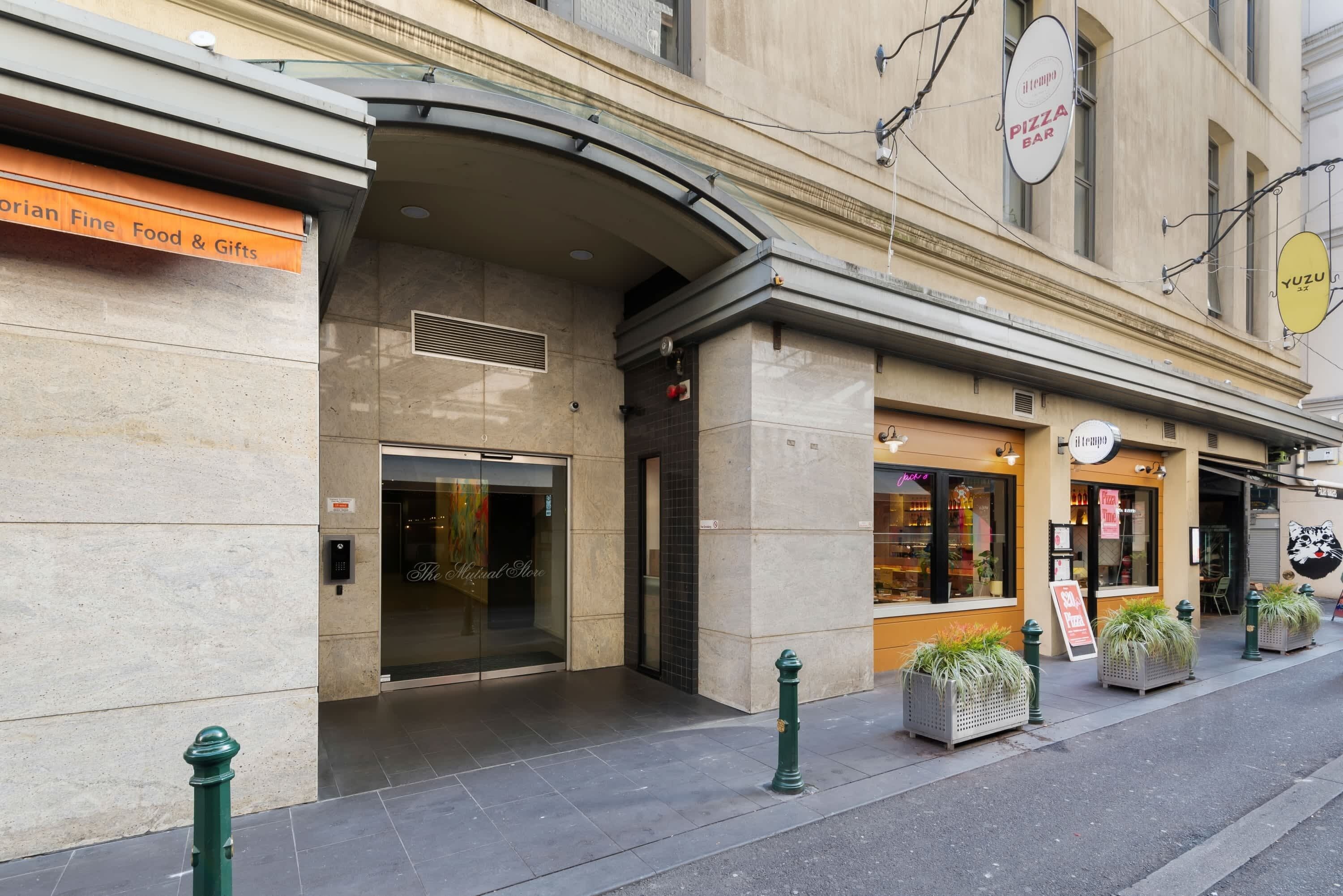 Un immeuble abritant un bar à pizzas, une boutique de produits gastronomiques et de cadeaux, ainsi qu’un restaurant avec une terrasse.