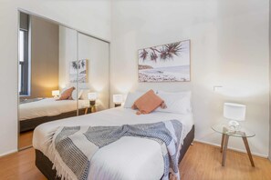 A bedroom with a bed, bedside lamps, a mirror, a wall-mounted picture, and a small table with a lamp. - Famous Degraves Lane Stunner with Parking! (Melbourne)