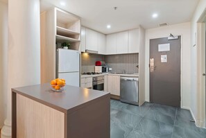 A modern kitchen with a central island, built-in appliances, and a tiled backsplash. - Famous Degraves Lane Stunner with Parking! (Melbourne)