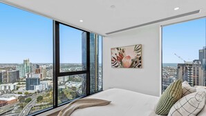 A bedroom with a large window, a bed, a pillow, and a painting. - Resort-style 3bed2bath Executive Southbank Pad (Southbank)