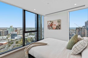 A bedroom with a large window, a bed, a pillow, and a painting. - Resort-style 3bed2bath Executive Southbank Pad (Southbank)