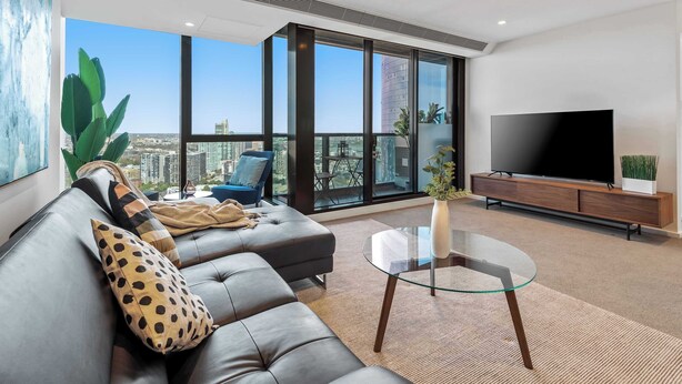 A modern living room with a sofa, a glass coffee table, a TV, and a city view. - Resort-style 3bed2bath Executive Southbank Pad (Southbank)