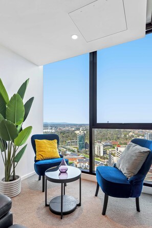A modern room with a large window, two blue chairs, a small table, and a potted plant. - Resort-style 3bed2bath Executive Southbank Pad (Southbank)