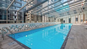 A modern indoor swimming pool with glass walls, a tiled floor, and a geometric wall design. - Resort-style 3bed2bath Executive Southbank Pad (Southbank)
