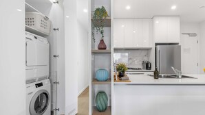Une cuisine moderne équipée d’un lave-linge encastré, d’un évier et d’un réfrigérateur.