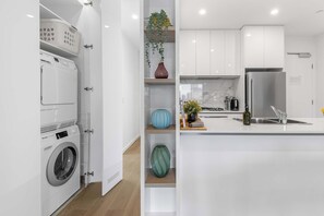 A modern kitchen with a built-in washing machine, a sink, and a refrigerator. - Executive 3BD City Haven with Parking + Views (Melbourne)