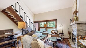 Un salon spacieux avec un escalier, une cheminée et une grande fenêtre.
