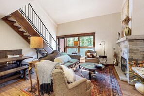 A spacious living room with a staircase, a fireplace, and a large window. - Ski-in/out Mountain view condo w/fast WiFi, fireplace, shared pool/hot tubs/WD (Vail)