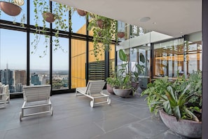 Ein moderner Lounge-Bereich mit großen Fenstern, Topfpflanzen und weißen Liegesesseln.