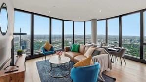 Een moderne woonkamer met een groot raam, een bank, een salontafel en een eethoek.