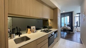 Een moderne keuken met houten kastjes, een roestvrijstalen spoelbak en een eethoek met een tafel en stoelen.