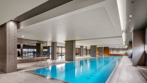 Een binnenzwembad met helder water, omringd door betegelde vloeren en wanden, met een modern architectonisch ontwerp.