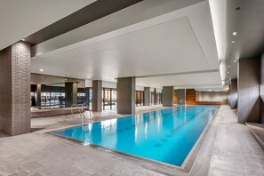 An indoor swimming pool with clear water, surrounded by a tiled floor and walls, with a modern architectural design. - Stunning, spacious, chic and central city pad (Melbourne)