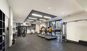 A gym with treadmills, weight machines, and a city view. - Stunning, spacious, chic and central city pad (Melbourne)