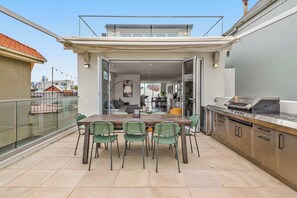 An outdoor dining area with a table and chairs, a kitchen with a grill, and a view of the cityscape. - Ultralux Absolute Beachfront with Extra Studio (Middle Park)