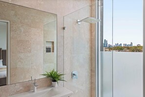 A modern bathroom with a large mirror, a showerhead, and a view of a cityscape. - Ultralux Absolute Beachfront with Extra Studio (Middle Park)