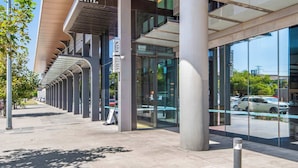 A modern building with a prominent P.M. sign, large glass windows, and a covered walkway. - 3BD beachside resort with parking, views and pool (Port Melbourne)