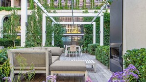 A covered outdoor patio with seating, a grill, and lush greenery. - 3BD beachside resort with parking, views and pool (Port Melbourne)