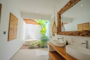 Un baño moderno con una bañera independiente, un lavabo y un espejo grande.