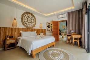 Ein modernes Schlafzimmer mit einem hölzernen Kopfteil, einem großen Bett, einem runden gewebten Teppich, einem Essbereich mit Tisch und Stühlen sowie einer wandmontierten Klimaanlage.