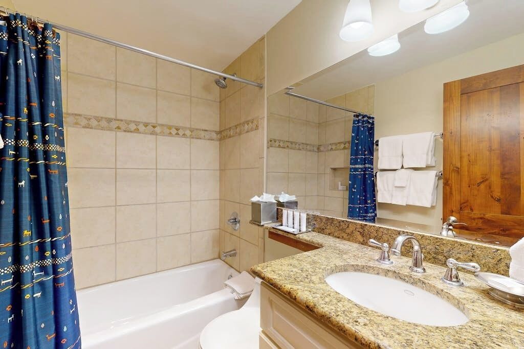 A bathroom with a bathtub, two sinks, a mirror, and a shower curtain.