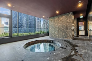 Ein moderner Poolbereich im Innenbereich mit einem runden Pool, großen Fenstern und Blick auf die Stadt.