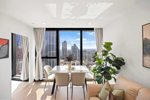 Ein modernes Wohnzimmer mit Essbereich, großen Fenstern und Blick auf die Stadt.