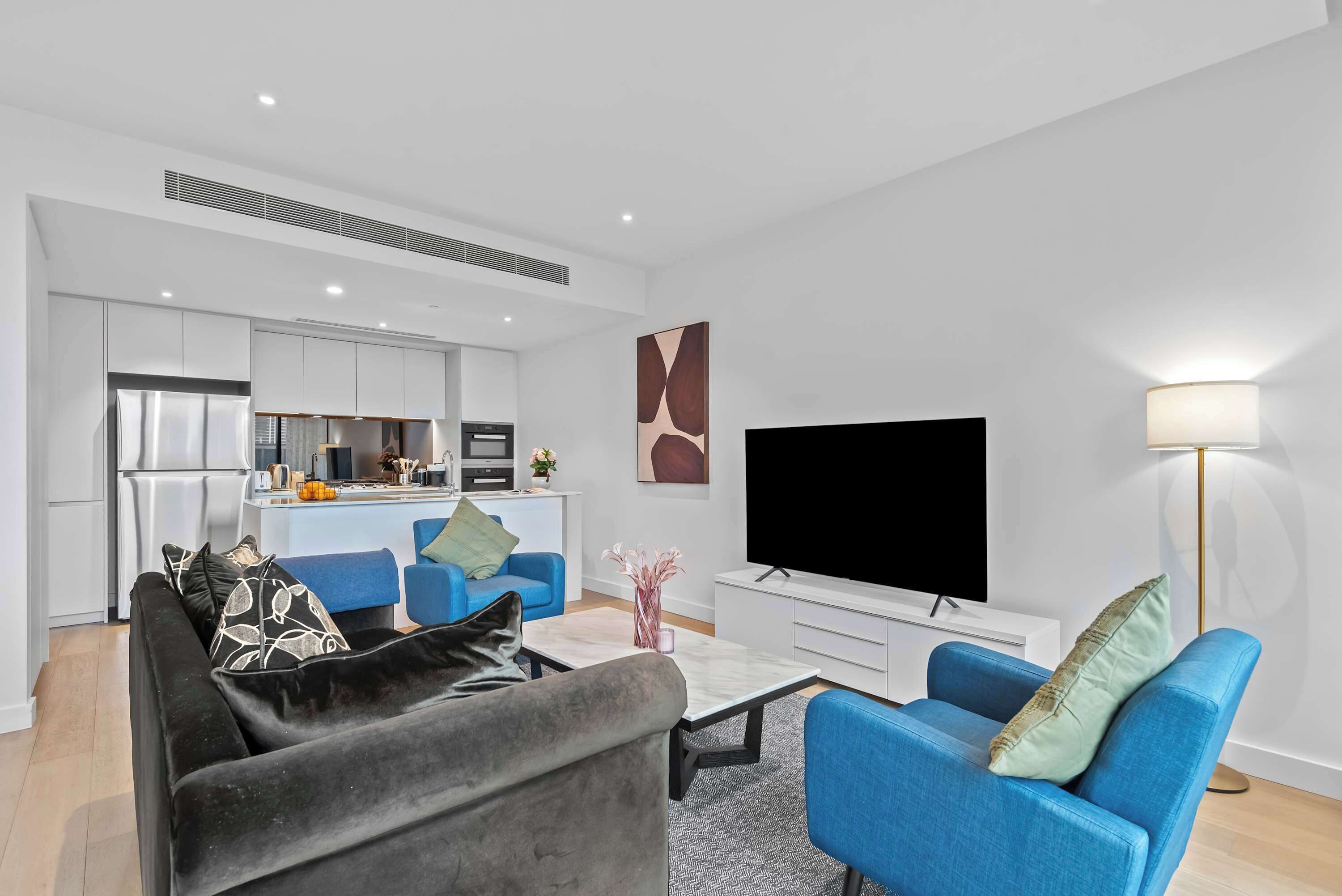 A modern living room with a sofa, a coffee table, a TV, and a lamp.