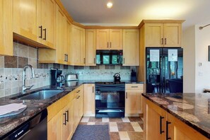 A kitchen with wooden cabinets, a Bosch dishwasher, a microwave, a stove, and a refrigerator. - Bright Mountain Retreat w/Shared Pool & Hot Tub & Mountain Views from Balcony (Vail)