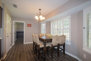 A dining area with a wooden table, six chairs, and a chandelier.