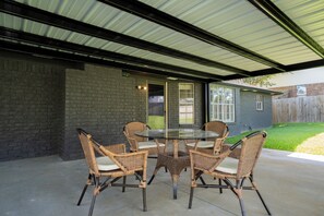 A covered patio with a glass table and wicker chairs. - Peaceful Small-Town Retreat with Everything Just Minutes Away (Longview)