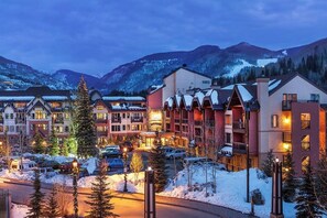 Ein Hotel mit mehreren Gebäuden, einem Parkplatz und verschneiten Bergen im Hintergrund.