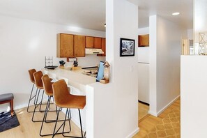 A modern kitchen with wooden cabinets, a white countertop, and bar stools. - Charming and stylish condo with pool, hot tub, washer/dryer, & WiFi (Vail)