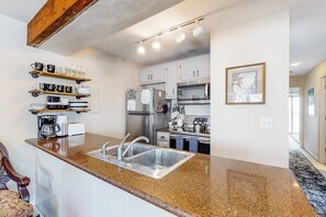Eine Küche mit Granit Arbeitsplatten, Edelstahlgeräten und einem eingebauten Backofen.