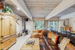 Ein gemütliches Wohnzimmer mit Kamin, Ledersofa, Holzschrank und einem großen Fenster.