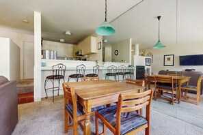 A dining area with a wooden table and chairs, a kitchen in the background, and a living room with a sofa. - Steps to Ski Shuttle Condo w/ Fireplace, WiFi & Shared Hot Tub/Seasonal Pool (Vail)