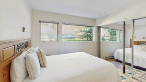 Une chambre à coucher avec un lit, une fenêtre et une porte-fenêtre coulissante donnant sur une autre pièce.