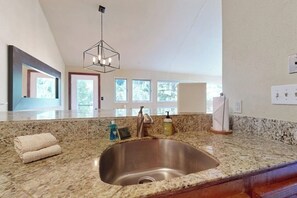 A modern kitchen with a granite countertop, stainless steel sink, and a pendant light. - Cozy condo with fireplace, pool & hot tub - steps to ski shuttle (Vail)