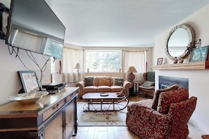 A living room with a sofa, a coffee table, a TV, and a fireplace. - Adorable Condo in w/Shared Pool, Hot Tub, WiFi, Washer/Dryer, & Free Shuttle (Vail)