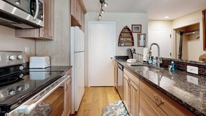 A kitchen with a stove, oven, microwave, and a sink with a countertop. - Adorable Condo in w/Shared Pool, Hot Tub, WiFi, Washer/Dryer, & Free Shuttle (Vail)