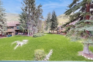 A residential area with houses, a well-maintained lawn, and surrounding trees. - Adorable Condo in w/Shared Pool, Hot Tub, WiFi, Washer/Dryer, & Free Shuttle (Vail)
