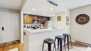 A kitchen with wooden cabinets, a white countertop, and a clock on the wall. - Beautiful East Vail Condo w/ Vail Village Ski Lockers/Free WiFi/Near Ski Shuttle (Vail)