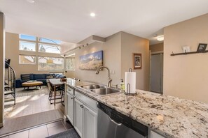 Eine moderne Küche mit Granit-Arbeitsplatten, Edelstahlgeräten und einem Essbereich mit einem blauen Sofa.