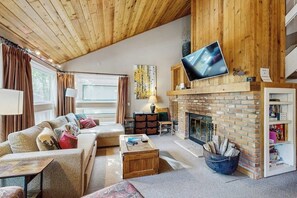 Ein gemütliches Wohnzimmer mit Kamin, Holzboden und einem an der Wand befestigten Flachbildfernseher.