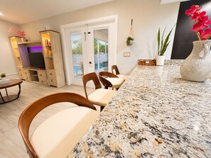 Eine moderne Küche mit einer Granit-Arbeitsplatte, Holzstühlen und einem Essbereich mit Blick auf den Garten.